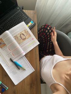 a person sitting at a desk with a book and laptop