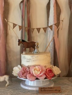 a small horse figurine sitting on top of a white cake with pink flowers