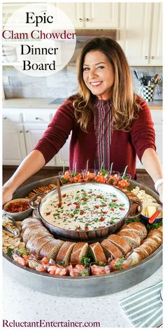 a woman standing in front of a large platter of food with the words epic clam chowder dinner board