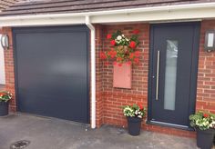 two blue garage doors with flower pots on the side and one has red flowers in it