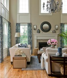 a living room filled with furniture and a fire place in front of a window covered in curtains