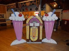 two ice cream sundaes are on display in an indoor area with wood floors