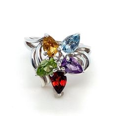 This multi-gemstone cluster ring features pear shaped amethyst, peridot, citrine, garnet, blue topaz, and a cubic  zirconia gemstone set in sterling silver. Size: 5.25  Metal Content: .925 Sterling Silver Face Height (North to South): 3/4" (19mm) Height of ring off of finger: 8mm Ring Shank width: 1mm Gemstones: Pear Cut Amethyst, Citrine, Peridot, Garnet, and Blue Topaz Round Cut White Cubic Zirconia Weight: 3.5 Grams Stamps: Ster Condition:  Excellent Pre-Owned   Items will ship in a gift box or pouch Each piece is thoroughly examined and refinished as needed by our professional jewelers, tested to guarantee metal content,  graded by our in-house GIA (Gemological Institute of America) Graduate Gemologist, and inspected for quality before being carefully packaged and promptly shipped. Tha Fine Jewelry Pear-shaped Multi-stone, Cluster Gemstones With Accent Stones As Gift, Pear-shaped Multi-stone Fine Jewelry Ring, Cluster Accent Stones Gemstones As Gift, Fine Jewelry Cluster Gemstones With Multi-stone, Multicolor Pear-shaped Gemstone Jewelry, Pear-shaped Multi-stone Ring For Gift, Pear Shaped Multi-stone Ring For Gift, Pear Shaped Multi-stone Ring As Gift