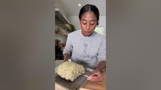 a woman is decorating a cake with icing on a cooling rack in the kitchen