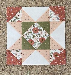 a patchwork piece with flowers on it sitting on the ground in front of a carpet