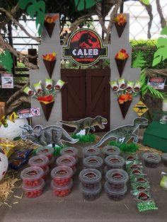 a table topped with lots of plastic cups filled with food next to a sign that says caleb