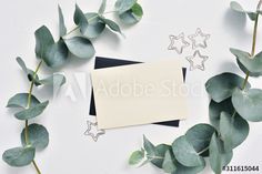 an empty card surrounded by green leaves and star cutouts on a white background with space for text