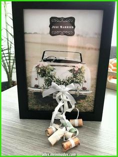 a framed photograph with wine corks tied to it and an old vw bug in the background