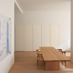 a large wooden table sitting in the middle of a room with white walls and wood flooring