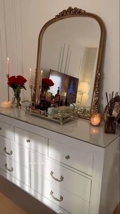 a white dresser topped with a mirror and candles