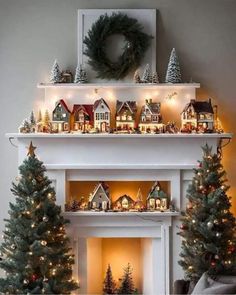 a fireplace decorated for christmas with small houses and trees on the mantel above it