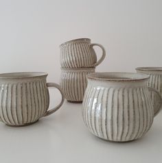 four white striped mugs sitting next to each other