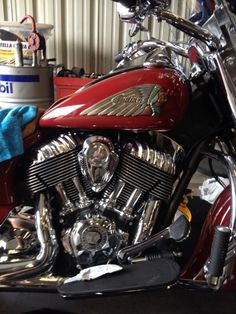 a red motorcycle parked in a garage next to a blue towel and some other items