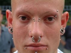 a man with piercings on his nose and nose ring in front of the camera