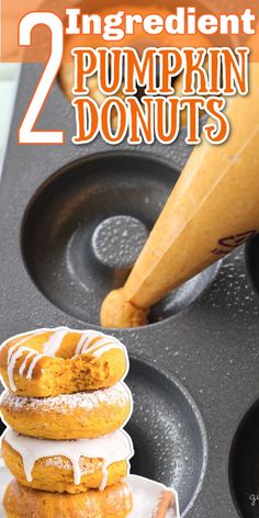 two pumpkin donuts stacked on top of each other in front of an orange cone