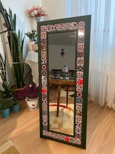 a mirror sitting on top of a wooden floor next to a table and potted plants