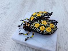 two yellow flowers are sitting on top of a white marble slab with beaded beads