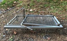 a metal bed frame sitting on top of a grass covered field next to a forest