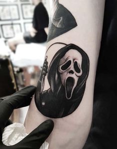 a person with a black and white tattoo on their arm wearing a grime mask