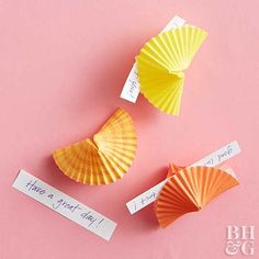 three orange and yellow paper fan shaped objects on a pink surface with words that say, i love you in two different languages