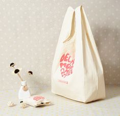 a white bag sitting on top of a table next to a small figurine