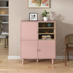 a pink cabinet sitting in the corner of a living room next to a brown chair