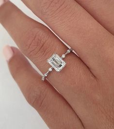 a woman's hand with an engagement ring on it and a diamond in the middle