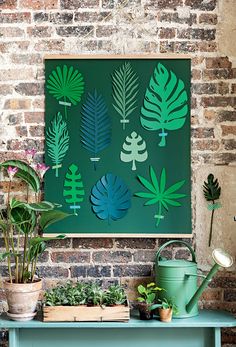 a green table topped with potted plants next to a wall mounted planter on top of a brick wall