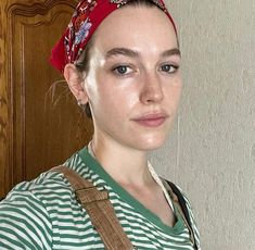 a woman with a red bandana on her head is standing in front of a door