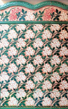 an ornately decorated wall with flowers and leaves on it's side, painted in green