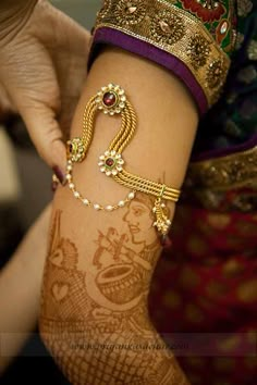 a woman's arm with henna and bracelets on it