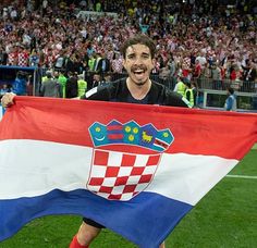 two soccer players holding croatia flags in front of a stadium full of people and fans