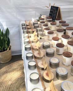 many candles are lined up on a table next to a potted plant and sign