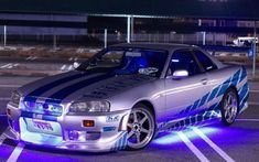 a silver car with blue stripes parked in a parking lot