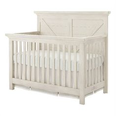 a white crib with a wooden headboard and mattress on it's side