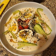 a white bowl filled with cucumber, eggs and black pepper sprinkles