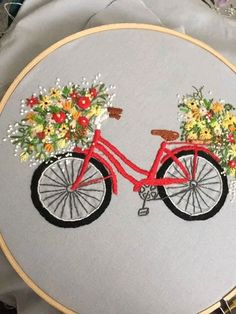 a red bicycle with flowers in the basket on it's handlebars is shown