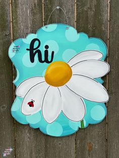 a blue and white sign with a ladybug on it that says hi in front of a wooden fence