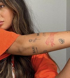 a woman wearing an orange shirt with tattoos on her arm