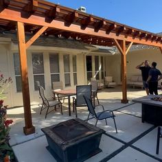 two men are standing in the back yard with an outdoor kitchen and grilling area