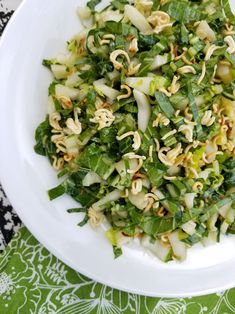 a white plate topped with green vegetables and sprouts