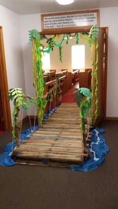 a wooden bridge made out of wood planks with plants on the sides and trees on the other side