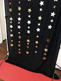 a black backdrop with gold stars on it and a red carpet in the foreground