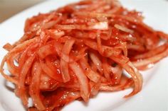 a white plate topped with sliced red onions on top of a wooden table next to a fork