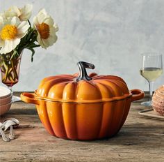 a pumpkin shaped casserole sitting on top of a wooden table next to other dishes