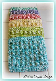 the crocheted dishcloth is multicolored and sits on a tile floor