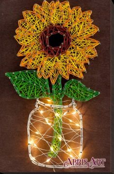 a string art sunflower in a mason jar with fairy lights on the outside and inside