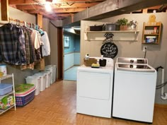 a washer and dryer in a laundry room next to each other with clothes hanging on the rack