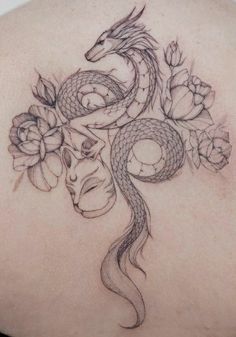 a woman's back with a dragon and flowers tattoo on her left side shoulder