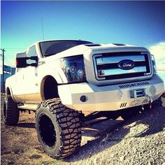 a white truck parked on top of a gravel field